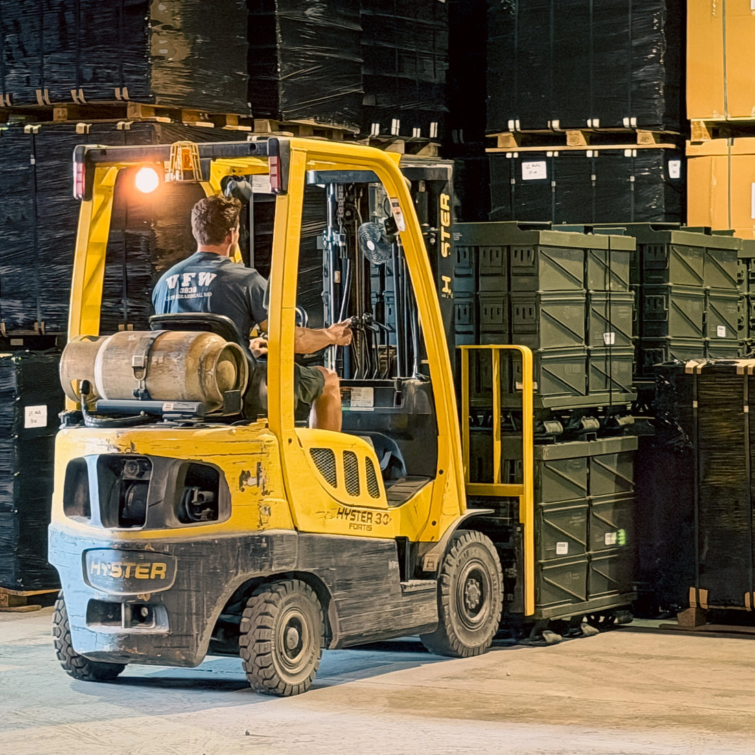 Forklift moving pallets of ammo cans in a warehouse