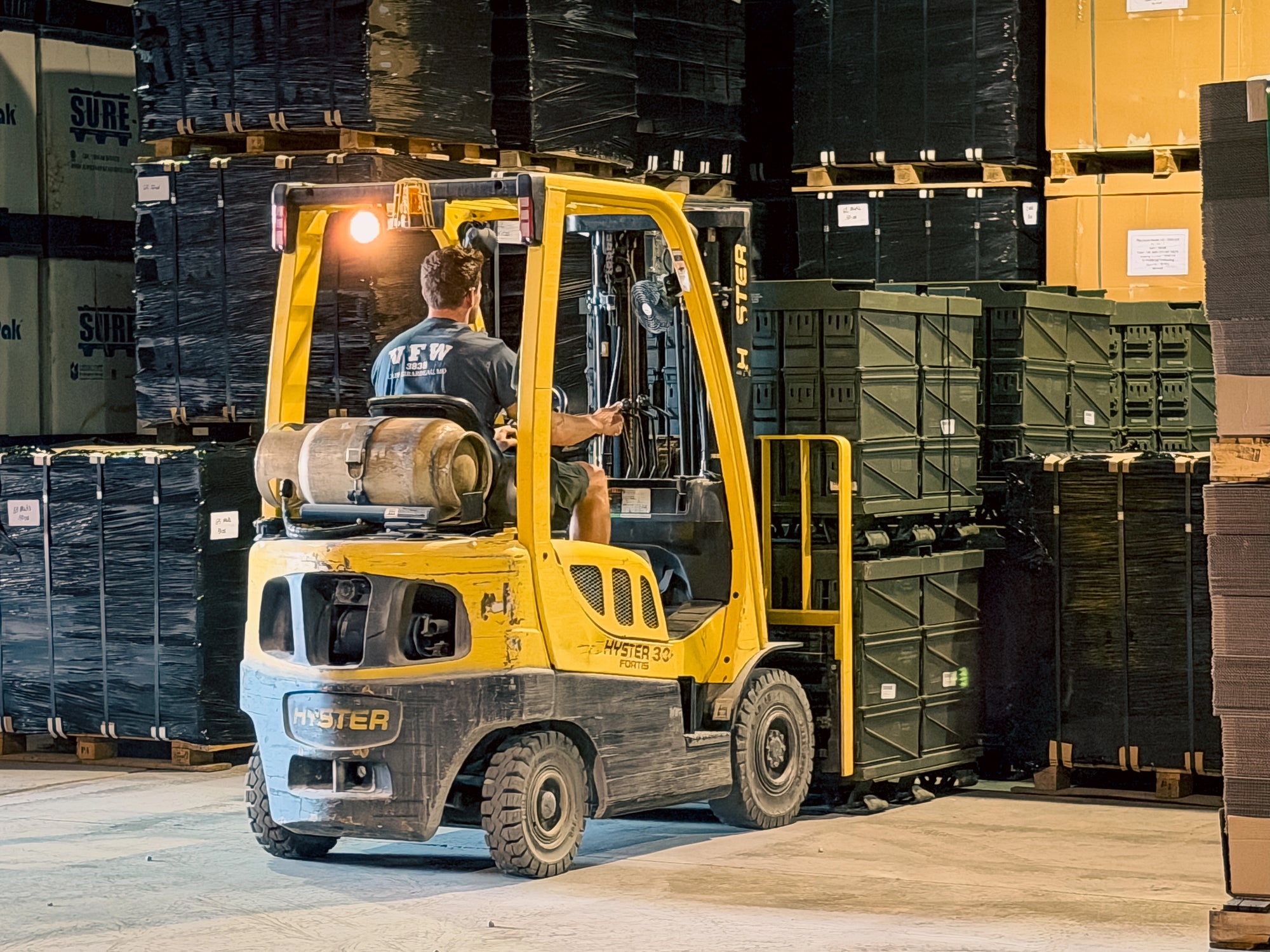 Forklift moving bulk pallets of ammo cans in a warehouse