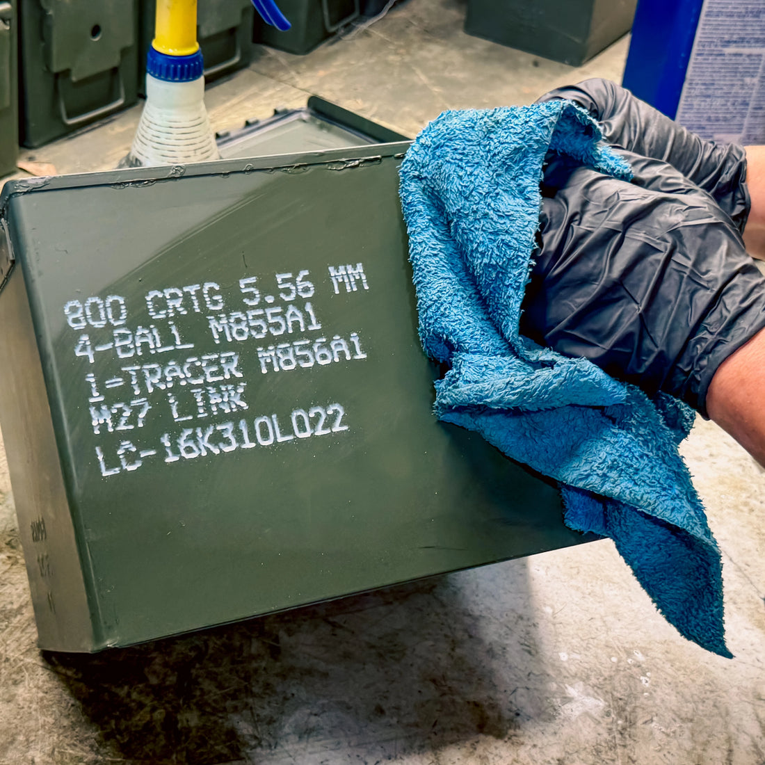 Person hand cleaning a surplus ammo can with a blue cloth